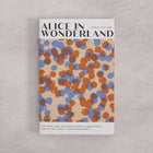 Bookishly edition of Alice in Wonderland by Lewis Carroll with a blue and rust dot-patterned dust jacket and personalised message printed on the front cover.