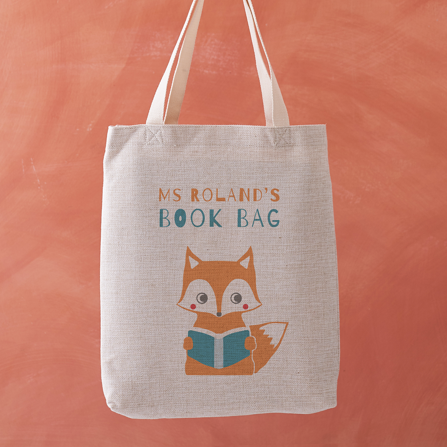 Personalised teacher tote bag with a fox reading a book and the text “Ms Roland’s Book Bag” printed above.