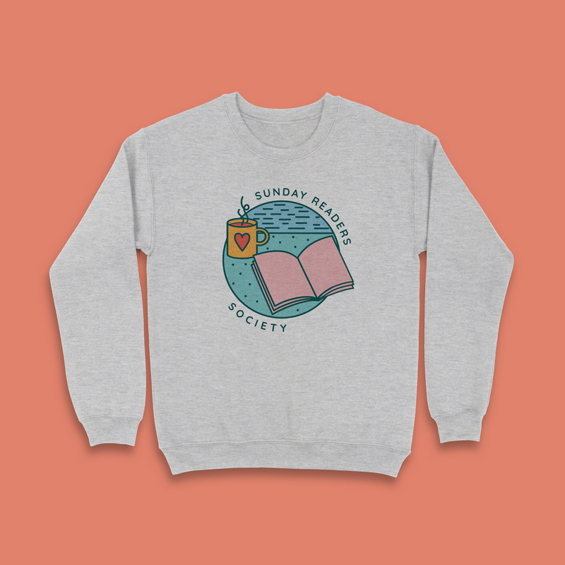 Grey sweatshirt with “Sunday Readers Society” design featuring an open book, mug with heart, and calm night sky illustration.