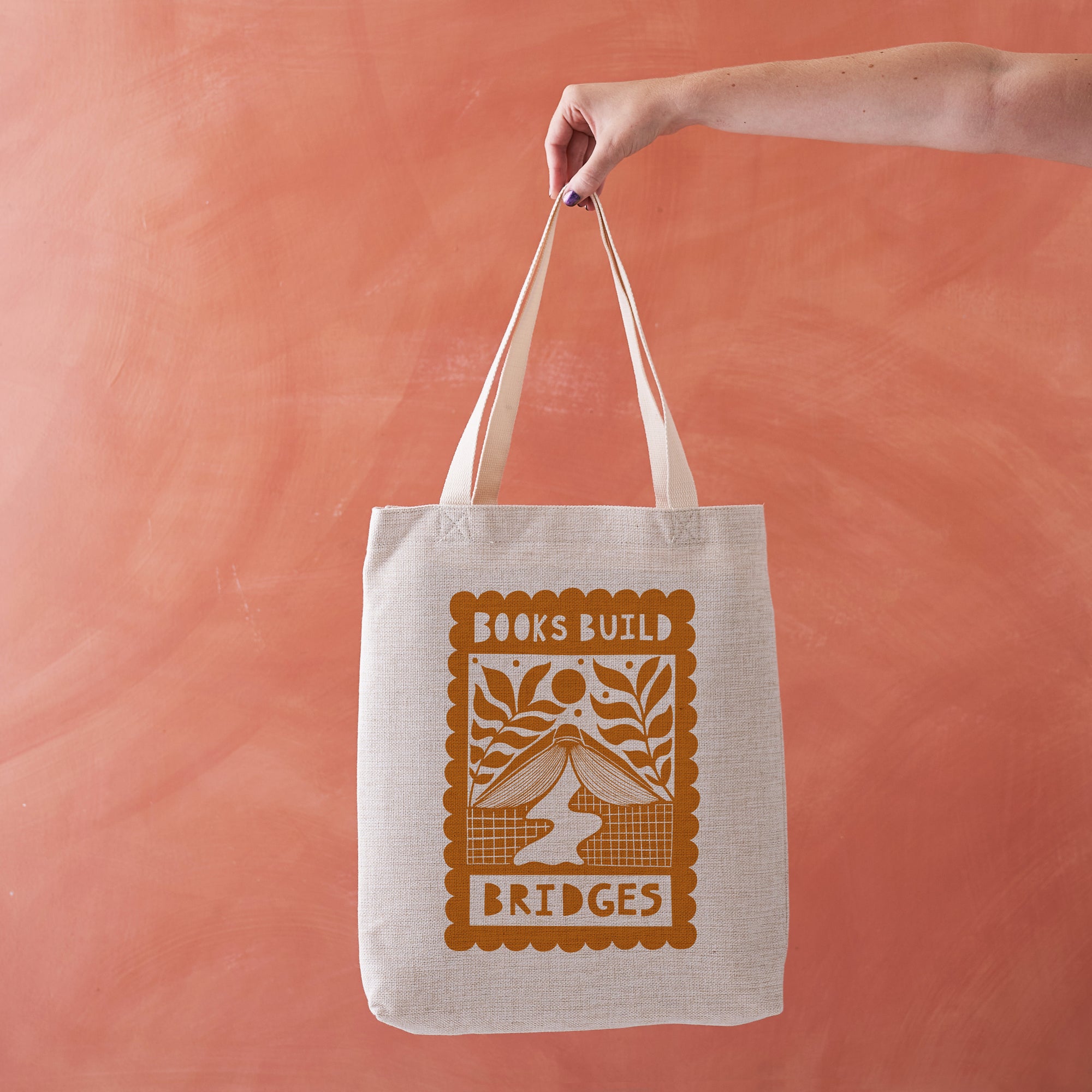 Linen-effect tote bag with red “Books Build Bridges” hand-lettered design