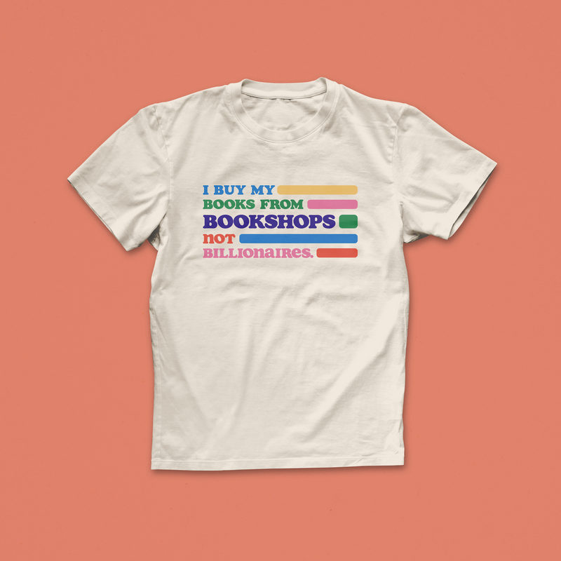 Bookshops Not Billionaires T-shirt with colourful rainbow text promoting ethical book buying, designed for indie bookshop supporters