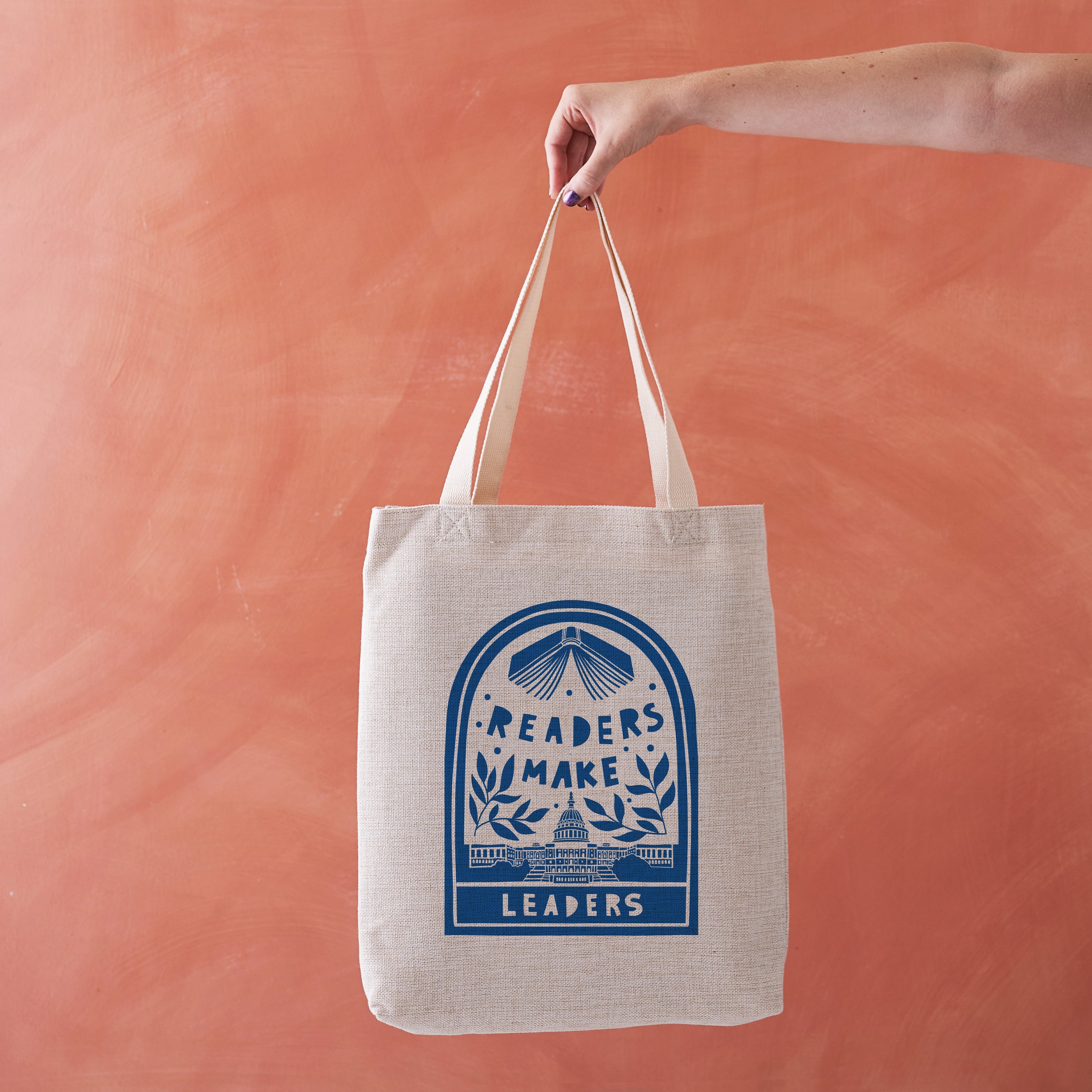 Natural-coloured tote bag with blue "Readers Make Leaders" hand-illustrated design