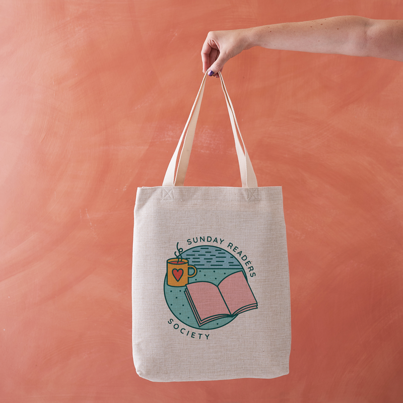 Natural tote bag with “Sunday Readers Society” design featuring an open book, night sky, and illustrated mug.