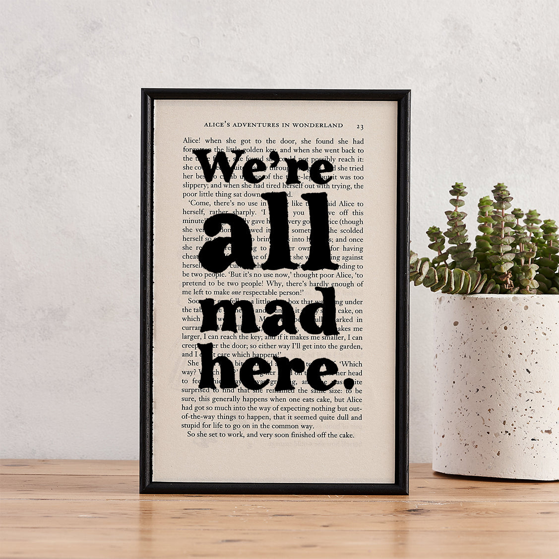 Framed book page print with the quote “We’re all mad here” from Alice’s Adventures in Wonderland.