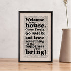 Framed book page print with the quote “Welcome to my house. Come freely. Go safely. And leave something of the happiness you bring!” from Dracula, styled beside a tall vase.