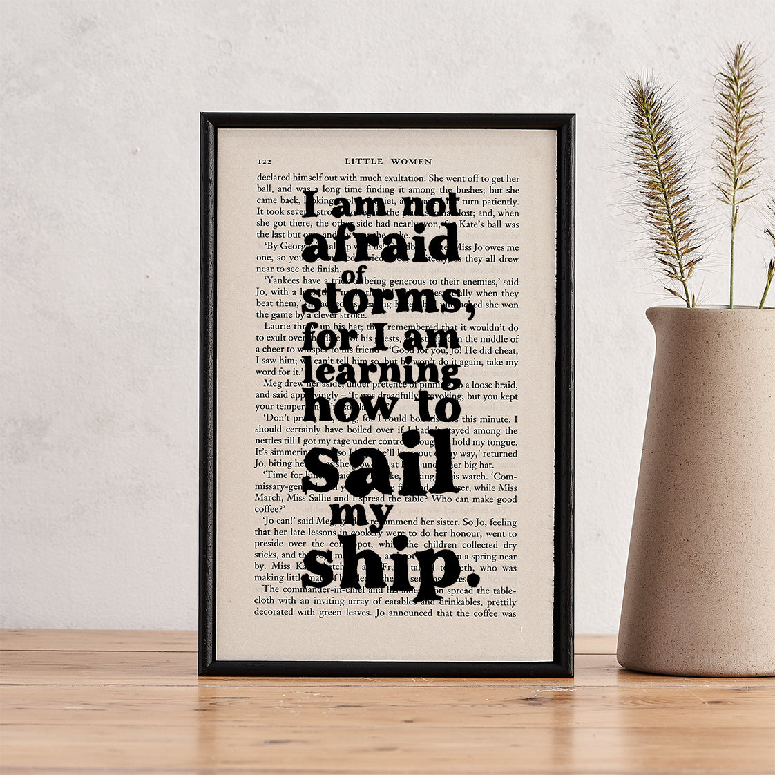 Framed quote print featuring “I am not afraid of storms” from Little Women on a book page