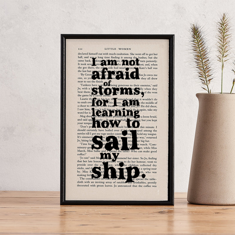 Framed quote print featuring “I am not afraid of storms” from Little Women on a book page