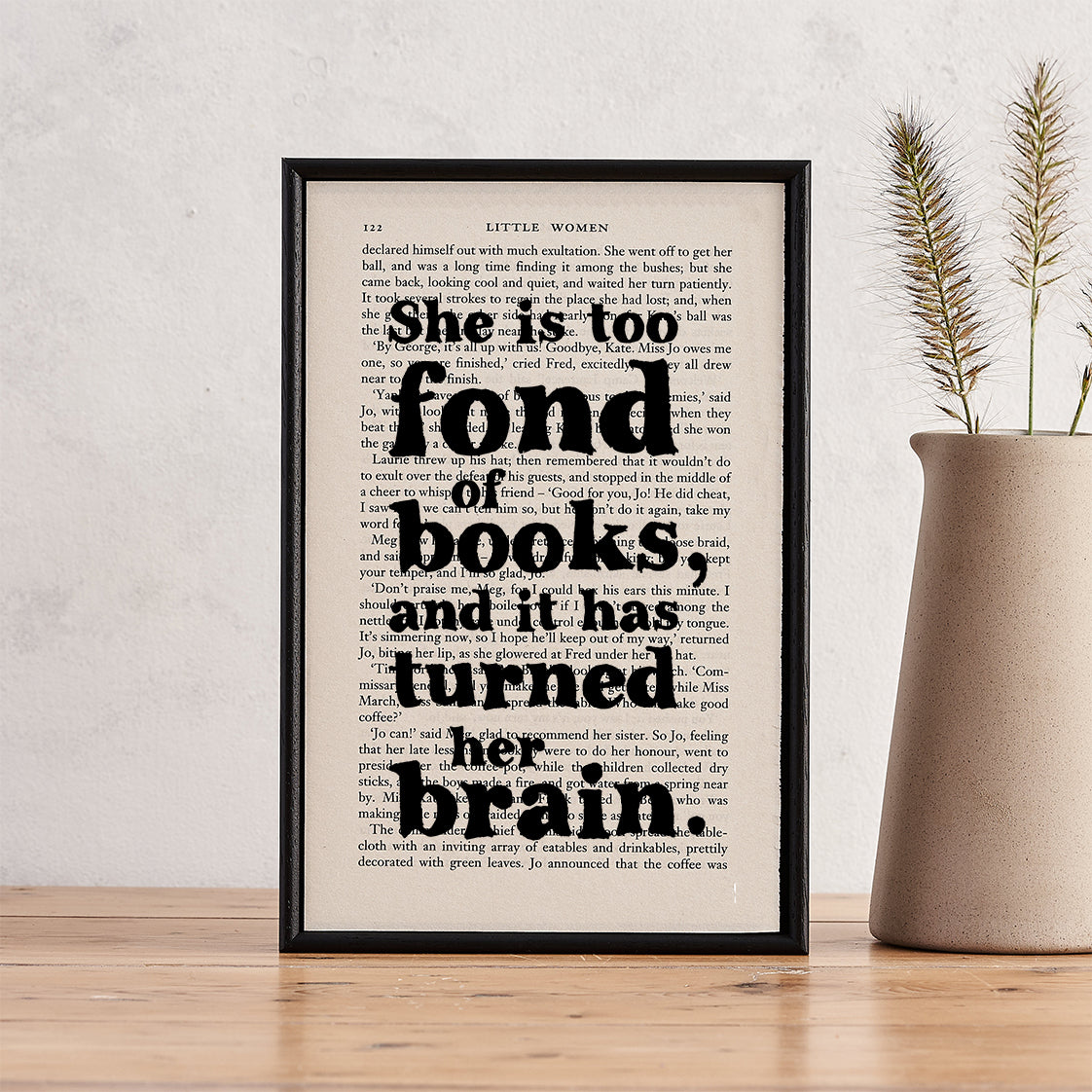 Framed book page print with the quote “She is too fond of books and it has turned her brain” from Little Women, styled with a ceramic vase.