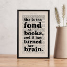 Framed book page print with the quote “She is too fond of books and it has turned her brain” from Little Women, styled with a ceramic vase.